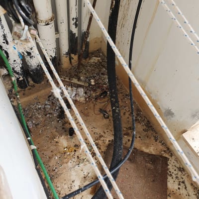 חבלים, צינורות ולכלוך על רצפה בפינת מבנה