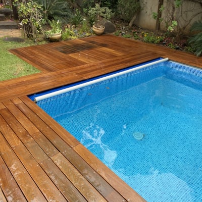 דק עץ ליד בריכת שחייה כחולה בגינה