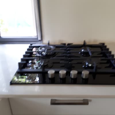 כיריים גז שחורות עם ארבעה מבערים וכפתורים כסופים