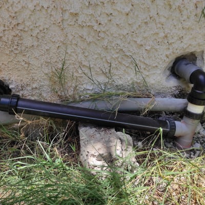 צינורות פלסטיק מחוברים לקיר חיצוני עם מחברים.