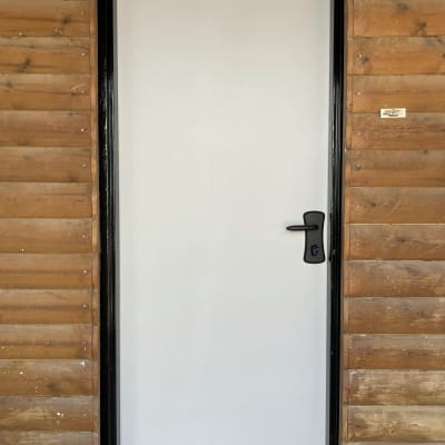 דלת לבנה עם ידית שחורה במסגרת עץ