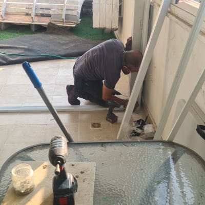 אדם מתקין מסגרת אלומיניום עם מברגה