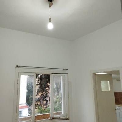 חדר צבוע בלבן עם חלון פתוח ונורה תלויה