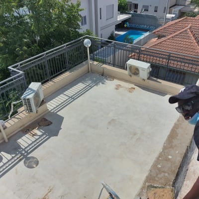 אדם על גג עם דלי צבע וכלי עבודה