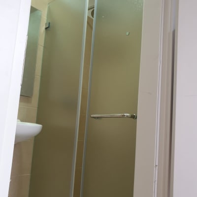 דלת זכוכית חלבית עם ידית מתכת בחדר רחצה