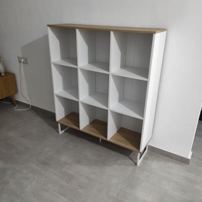 ארון מדפים לבן עם מדפי עץ, עומד על רצפה אפורה