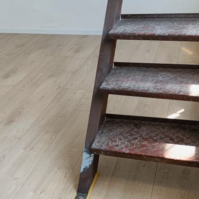 רצפת פרקט עץ בהירה ליד מדרגות מתכת