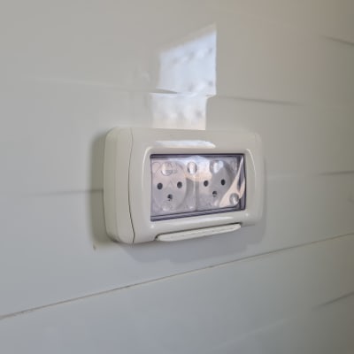 שקע חשמלי עם כיסוי שקוף על קיר לבן