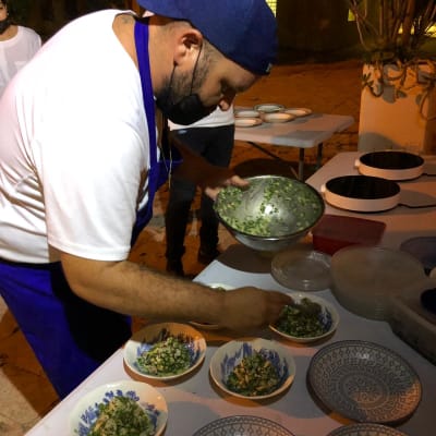 שף מכין מנות סלט בקערות על שולחן חיצוני