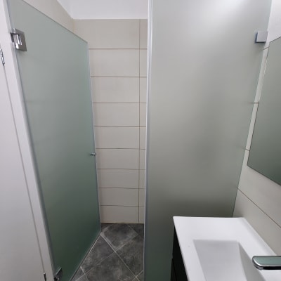 מקלחון עם דלתות זכוכית חלבית ורצפת אריחים אפורה