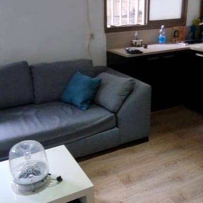 ספה אפורה עם כרית כחולה, שולחן לבן עם רמקול