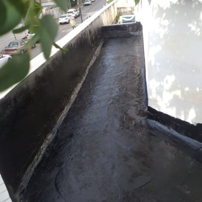 איטום גג עם חומר שחור על משטח בטון