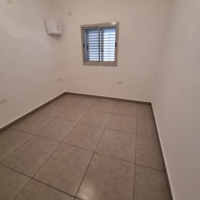 חדר ריק עם רצפת אריחים נקייה וקירות לבנים