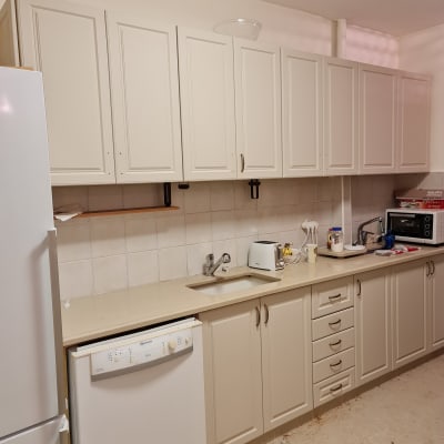 מטבח עם ארונות לבנים, כיור, מדיח כלים וטוסטר