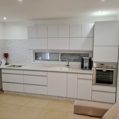 מטבח מודרני עם ארונות לבנים ומשטח עבודה