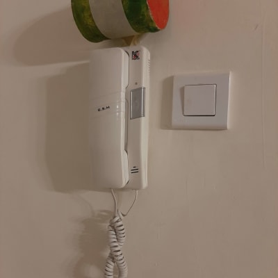 אינטרקום לבן עם שפופרת תלויה על הקיר