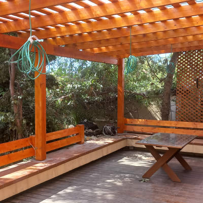 פרגולה מעץ עם ספסלים ושולחן בגינה