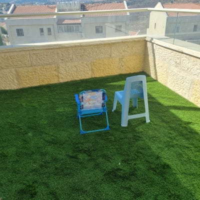 דשא סינתטי עם כיסאות פלסטיק בגינה