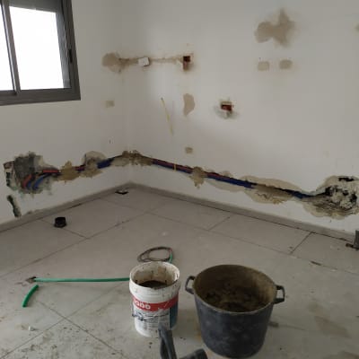 צינורות חשופים בקיר, דלי עם חומר בנייה