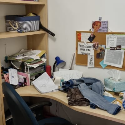 שולחן עבודה מבולגן עם ניירות, בגדים וכלי כתיבה