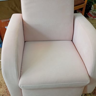 כורסה מרופדת בצבע בהיר על רצפת עץ