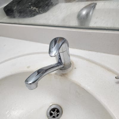 ברז כרום על כיור לבן עם כתמי לכלוך