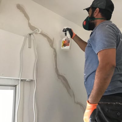 אדם מרסס חומר איטום על קיר סדוק