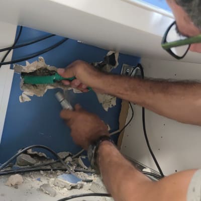 טכנאי רשתות עובד עם כבלים בתוך קיר