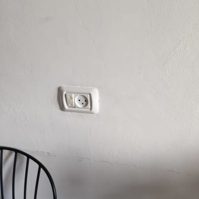 שקע חשמל בקיר לבן עם מתג לידו