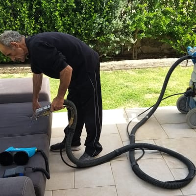 אדם מנקה ספה עם מכונת ניקוי מקצועית