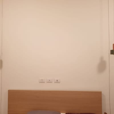 שני מנורות תלויות מעל מיטה עם שקעים בקיר