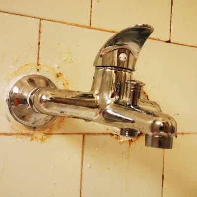 ברז כרום מותקן על קיר אריחים לבנים