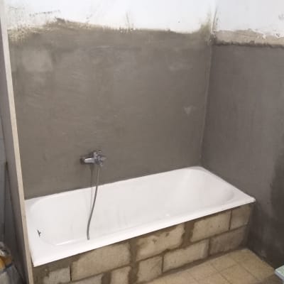 אמבטיה בשיפוץ עם קירות מטויחים ובלוקים חשופים