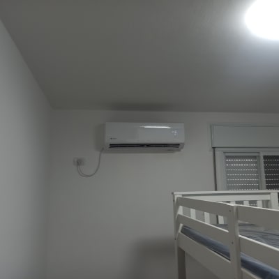 מזגן מותקן על קיר לבן בחדר שינה