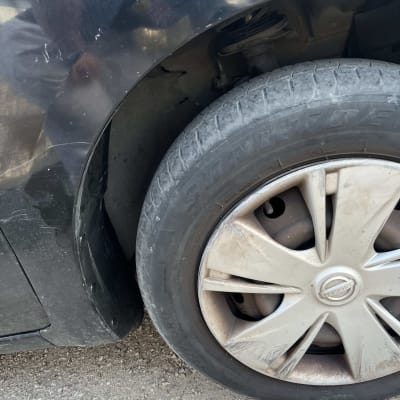 פגוש רכב שחור עם שריטות וגלגל קדמי