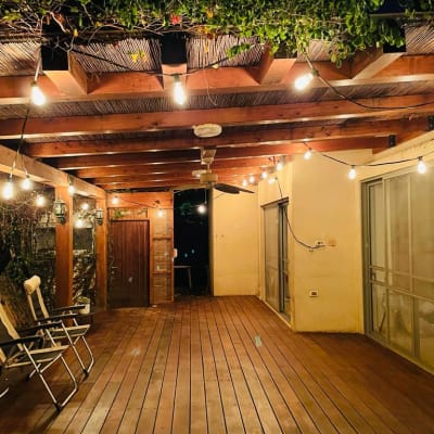 מרפסת עץ עם תאורה תלויה וכיסאות מתקפלים