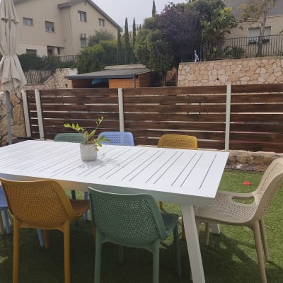 שולחן לבן עם כסאות צבעוניים בגינה על דשא סינתטי