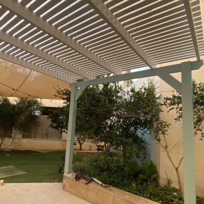 פרגולה מעץ עם צמחים מסביב בגינה