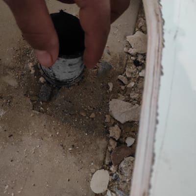 יד מחזיקה צינור מתכת בבור באדמה