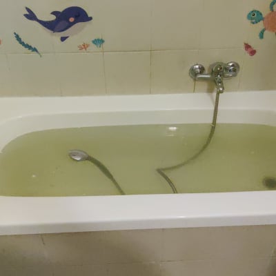 אמבטיה עם מים עכורים וברז מקלחת