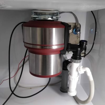 מכשיר טוחן אשפה מתחת לכיור עם צינורות חיבור