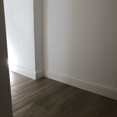 רצפת עץ כהה וקיר לבן עם פנלים