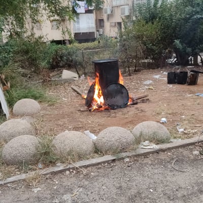 חבית מתכת בוערת עם מכסים על האש