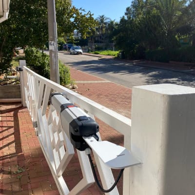 שער חשמלי לבן עם מנוע מותקן על עמוד