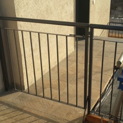 מעקה מתכת עם שער על מרפסת מרוצפת