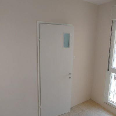 דלת לבנה עם חלון קטן על קיר צבוע