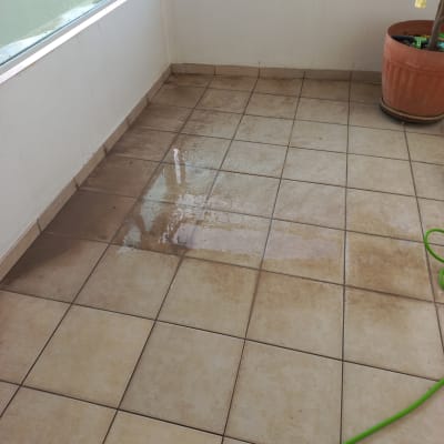 רצפת מרפסת עם אריחים רטובים וצינור ירוק