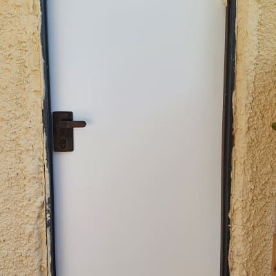 דלת לבנה עם ידית שחורה ומסגרת מתכת