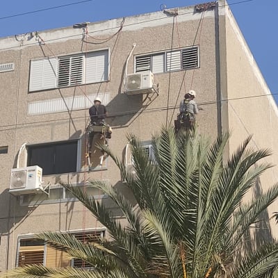 עובדים על חבלים אוטמים קיר חיצוני של בניין