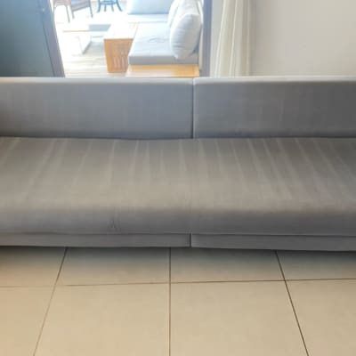 ספה אפורה נקייה על רצפת אריחים בהירה